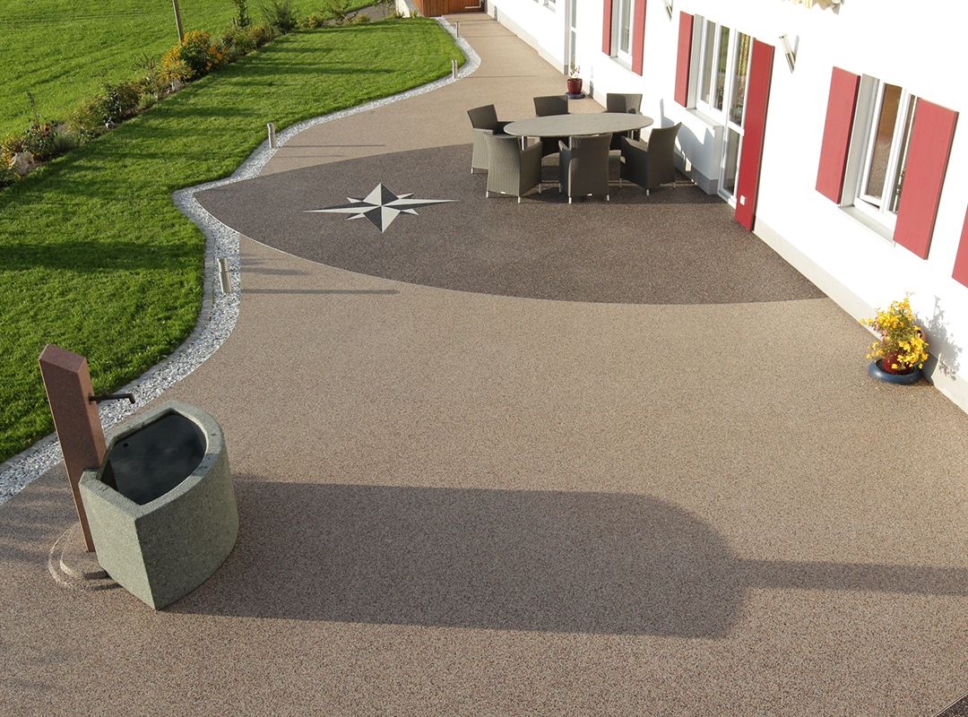 Eingearbeitetes Muster in eine Steinteppich-Terrasse mit einer Sitzgruppe und Brunnen