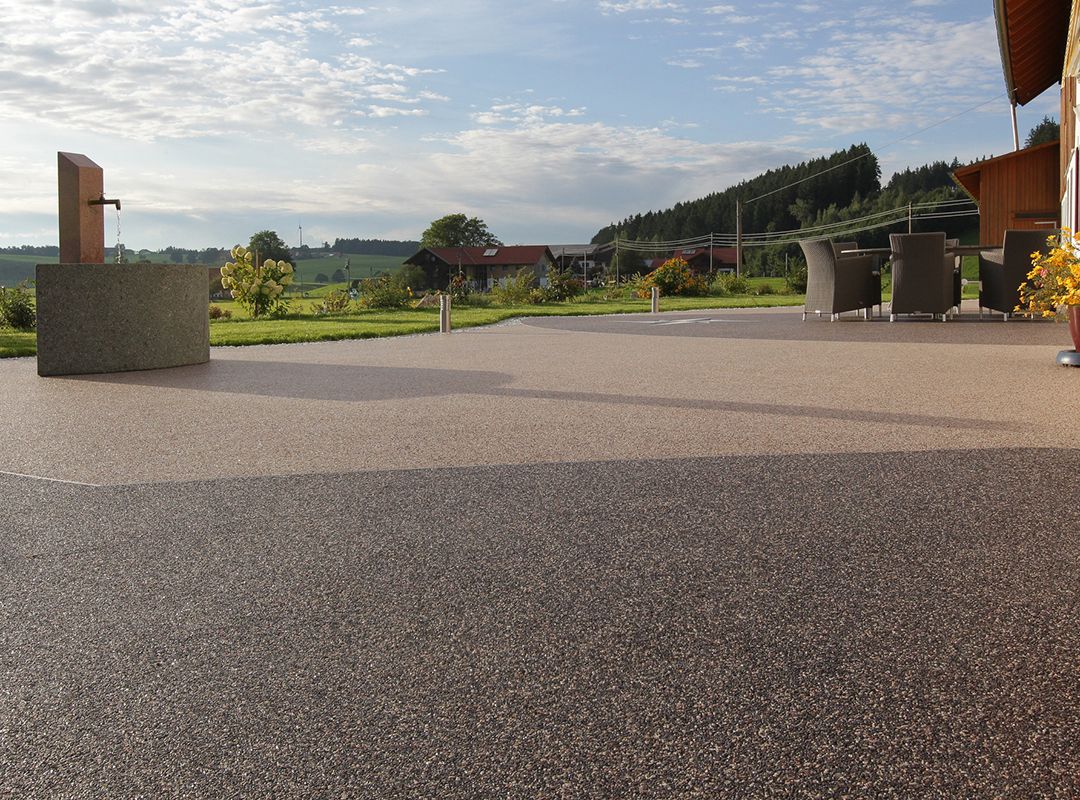 Steinteppich-Terrassen-Beschichtung mit Brunnen und Gartenmöbeln im Freien